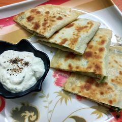 A picture of Aloo Afghani Bolani served with cheesy yoghurt sauce.