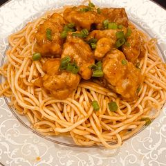 A picture of Orange Chicken with spicy spaghetti.