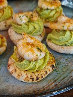 Una foto de Mini pan de pita con hummus de aguacate y gambas