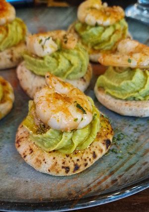 Una foto de Mini pan de pita con hummus de aguacate y gambas