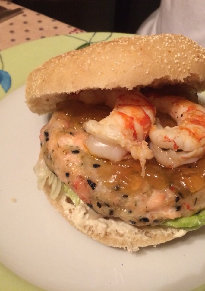 Una foto de Hamburguesa de salmón y gambas con salsa de eneldo y cebolla caramelizada