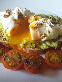 Una foto de Tostada aguacate, sésamo tostado y huevo poché con cherrys