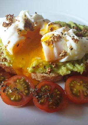Una foto de Tostada aguacate, sésamo tostado y huevo poché con cherrys