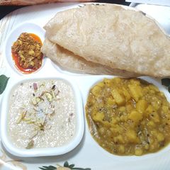 A picture of Soft Puri with Aloo ki bhujiya, Kheer & achar.