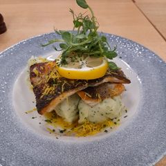 A picture of Seabass with Garlic champ drizzled with lemon and caper butter.
