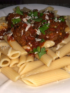 A picture of Penne pasta with meat ball sauce.