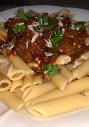 A picture of Penne pasta with meat ball sauce.