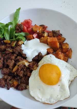 Una foto de Bowl carne picada, boniato, arroz integral, huevo. Canónigos, tomate y salsa de yogurt