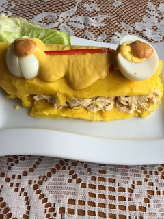 Una foto de Causa rellena de pollo bañada en salsa a la huancaína