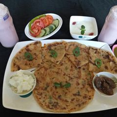 A picture of Aloo parantha with curd and rose sweet lassi.