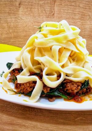 A picture of Tagliatelle bolognese with spinach.