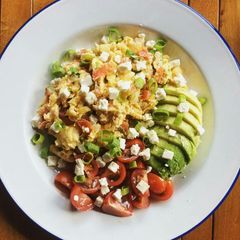 A picture of Scrambled eggs with tomatoes and avocado.