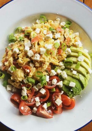 A picture of Scrambled eggs with tomatoes and avocado.