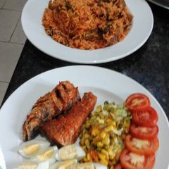 A picture of Jollof Rice peppered glazed fish and corn veggies.