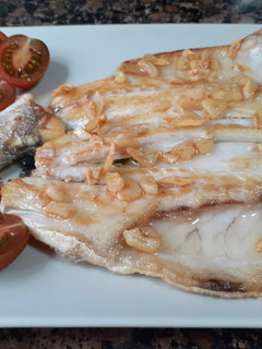 Una foto de Lubina a la plancha con ajos confitados