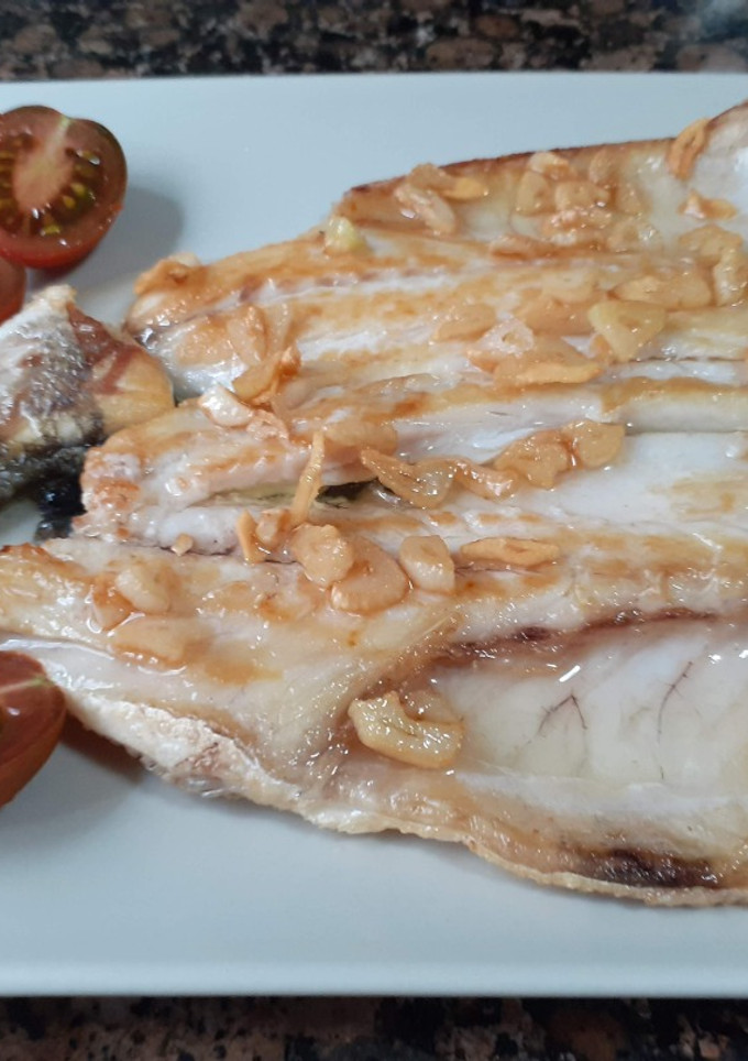 Una foto de Lubina a la plancha con ajos confitados