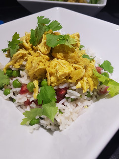 Una foto de Curry de pollo y coco tostado sobre arroz basmati con guisantes y granada