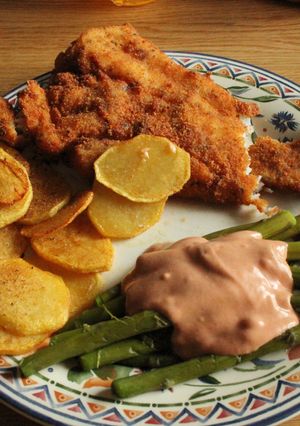 Una foto de Pescado frito en milanesa, tomate con ajo, espárragos, papas fritas