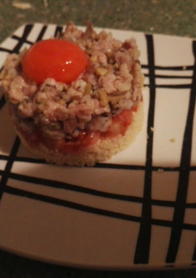 Una foto de Tartar ibérico con tomates y yema curada sobre cama de couscous
