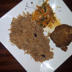 A picture of Pilau with chicken and salad on the side.