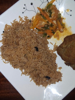 A picture of Pilau with chicken and salad on the side.