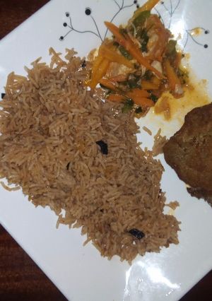 A picture of Pilau with chicken and salad on the side.