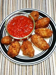 A picture of Potato nuggets served with marinara sauce.