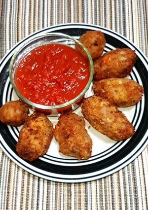 A picture of Potato nuggets served with marinara sauce.