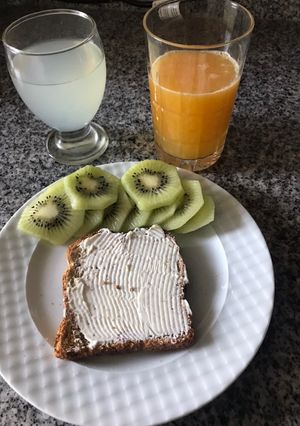 Una foto de Así arrancamos las mañanas, vaso de agua con limón, un jugo de naranja exprimido, tostada y fruta