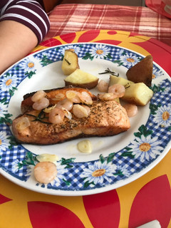 Una foto de Salmón a la plancha, con camarones en mantequilla y ajos acompañado de papas al horno con romero