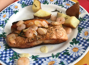 Una foto de Salmón a la plancha, con camarones en mantequilla y ajos acompañado de papas al horno con romero