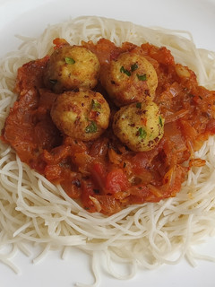 A picture of Spaghetti in bolongnese sauce with golden paneer balls.