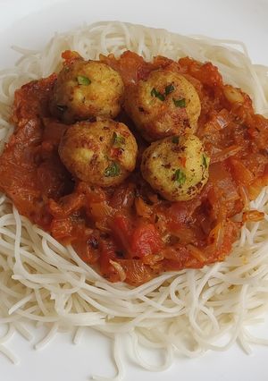 A picture of Spaghetti in bolongnese sauce with golden paneer balls.
