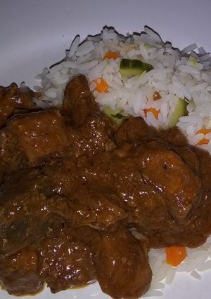 A picture of Rice with cucumbers, carrots and beef stew.