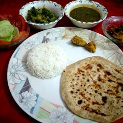 A picture of Dal,rice,chapati,bhindi with salad and pickle.
