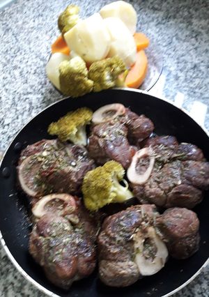 Una foto de Osobuco a las finas hierbas con brócoli acompañado de verduras