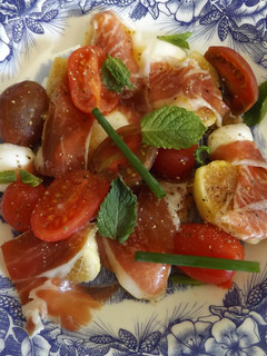 Una foto de Plato de higos, mozzarella, jamón y tomatitos con cebollino y hierba buena