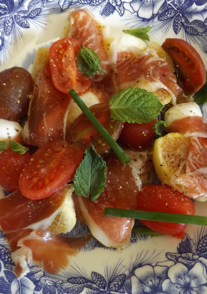 Una foto de Plato de higos, mozzarella, jamón y tomatitos con cebollino y hierba buena