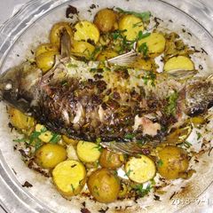 A picture of Baked whole fish with lemon and potato.