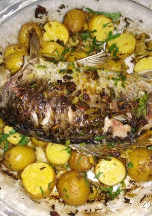A picture of Baked whole fish with lemon and potato.