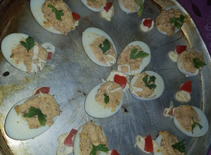 Una foto de Huevos rellenos de atún decorado con mayonesa y tomates