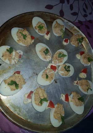 Una foto de Huevos rellenos de atún decorado con mayonesa y tomates