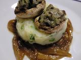Champiñones rellenos sobre puré de patatas en cama de cebolla