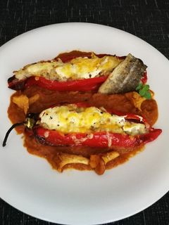 Una foto de Pimientos rellenos con bacalao y arroz sobre salsa de tomate