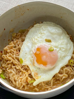 A picture of Jah Jan Mien (instant packet noodles) with peanut butter, spring onions topped with fried egg.