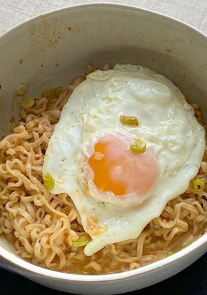 A picture of Jah Jan Mien (instant packet noodles) with peanut butter, spring onions topped with fried egg.