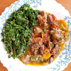 A picture of Stewed Goat meat with sauted kales.