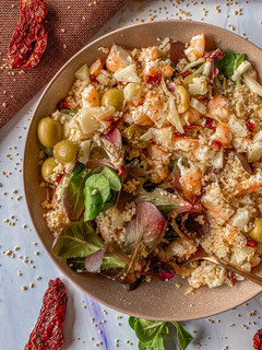 Una foto de Ensalada de canónigos, cous cous y langostinos