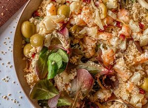 Una foto de Ensalada de canónigos, cous cous y langostinos