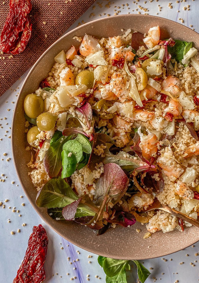 Una foto de Ensalada de canónigos, cous cous y langostinos